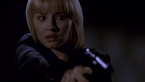 a woman is pointing a gun at the camera in the dark