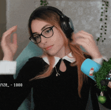 a woman wearing glasses and headphones is sitting in front of a microphone with the number 1000 in the corner