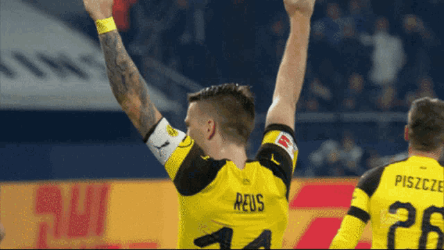 a soccer player wearing a yellow jersey with the name reus on the back
