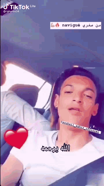 a man in a white shirt is sitting in a car with his eyes closed and a heart next to him .