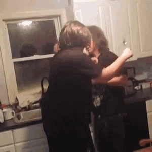 a couple hugging each other in a kitchen with white cabinets