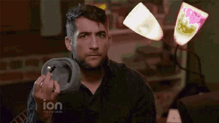 a man is holding a pair of socks in front of a ion television sign