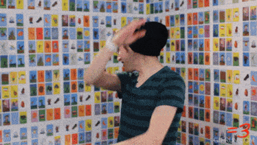 a man is standing in front of a wall of cards with the number 3 on the bottom right
