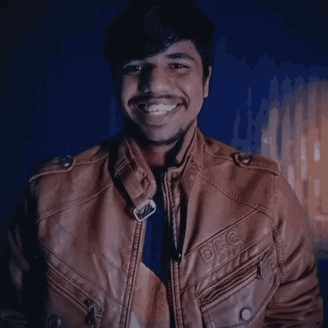a man wearing a brown leather jacket with d & g embroidered on it gives a thumbs up