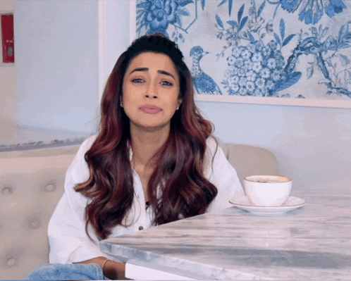a woman is sitting at a table with a cup of coffee