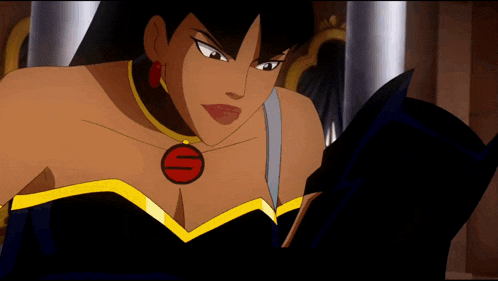 a woman in a black dress with a red s on her chest is reading a book