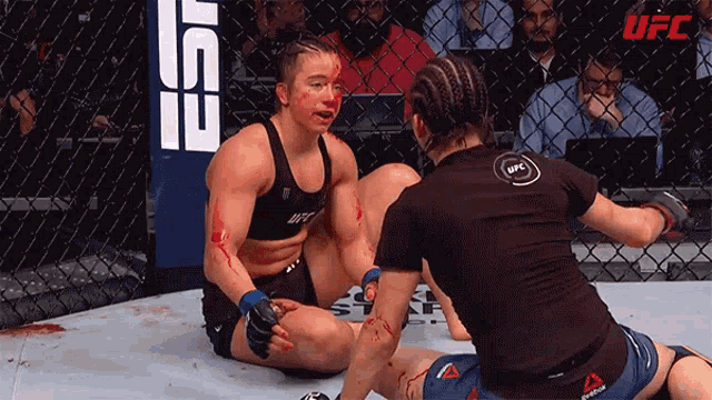 two women in a boxing ring with ufc written on the fence