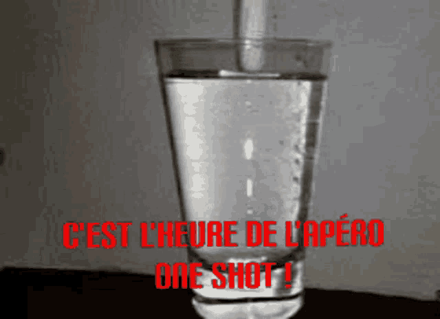 a glass of water with the words c'est l' heure de l' apéro one shot in red