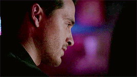 a close up of a man 's face in a dark room with a purple background .