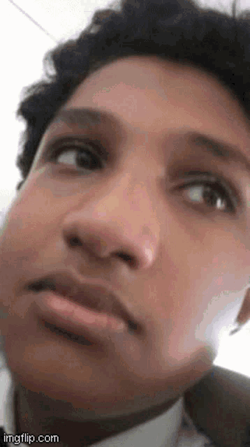 a close up of a young man 's face with his eyes closed and a serious look on his face .