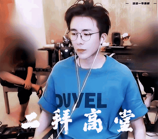 a young man wearing glasses and a blue duvel t-shirt