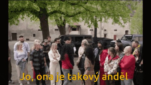 a group of people standing in front of a tree with the words jo ona je takový andel written in yellow