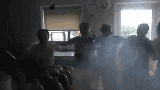 a group of people are dancing in a dark room with a lot of bottles