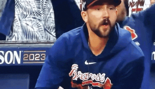 a man wearing a braves jersey is sitting in a dugout .