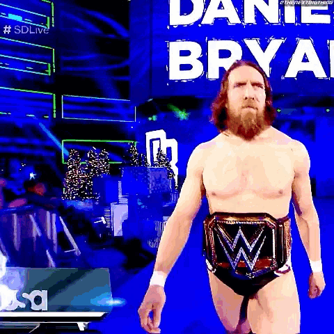 a wrestler without a shirt is walking on a stage with a wwe belt around his waist .