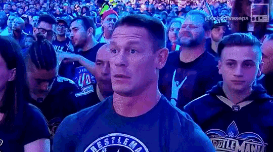a man in a wrestler 's shirt is standing in a crowd of people .