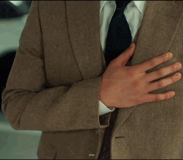 a man in a suit and tie is holding his hand to his chest