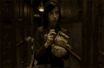 a woman walking down a hallway holding a bag
