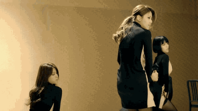 a woman in a black and white dress is standing in a room with two other women