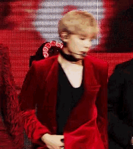 a man in a red jacket is standing in front of a red background