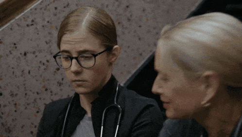 a woman with glasses and a stethoscope around her neck looks at another woman