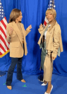 two women are standing in front of an american flag