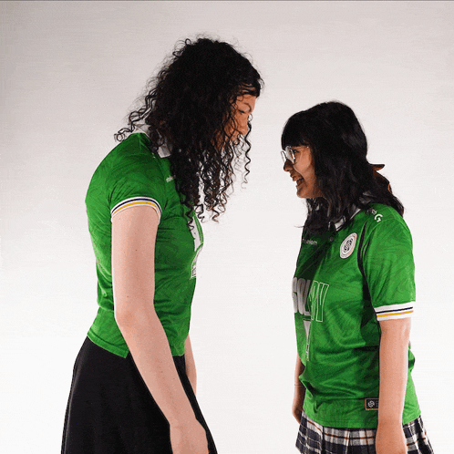 two women standing next to each other with one wearing a green jersey that says ' sydney ' on the front