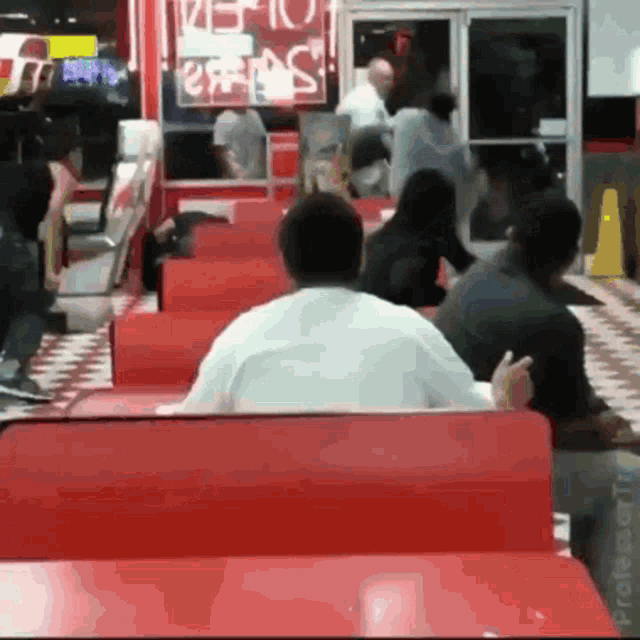 a group of people sitting in a diner with a sign that says ' steak '