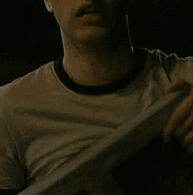 a close up of a man 's face in a t-shirt with a black collar .