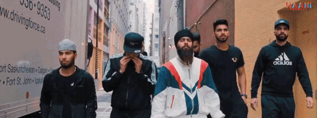 a group of men are walking down an alleyway and one of them is wearing an adidas hoodie