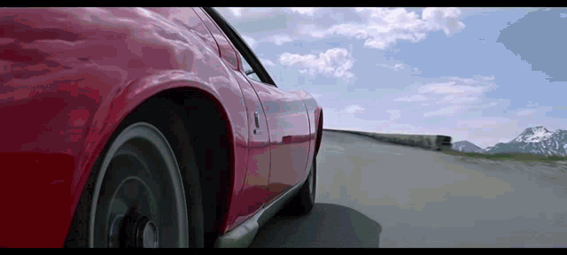 a red sports car is driving down a road