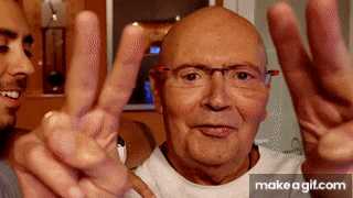 a bald man with glasses is making a peace sign with his hands