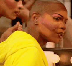 a woman in a yellow shirt is getting her makeup done