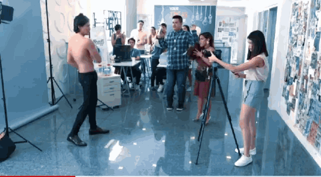 a man without a shirt is being filmed in front of a wall that says your ideas