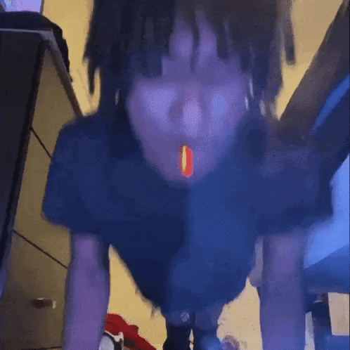 a man with dreadlocks is smoking a cigarette in a bedroom .