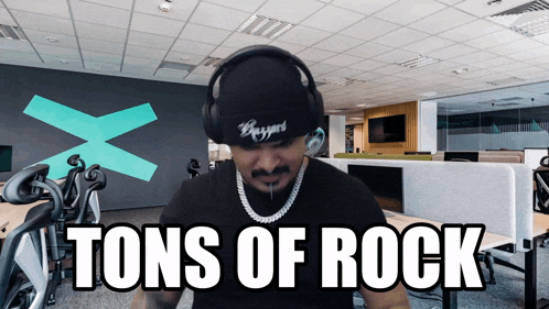 a man wearing headphones says " tons of rock " in front of an office