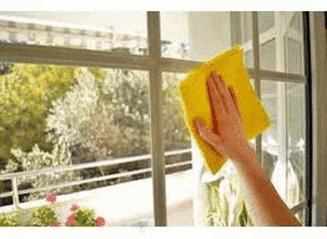 a person is cleaning a window with a yellow cloth and a towel .