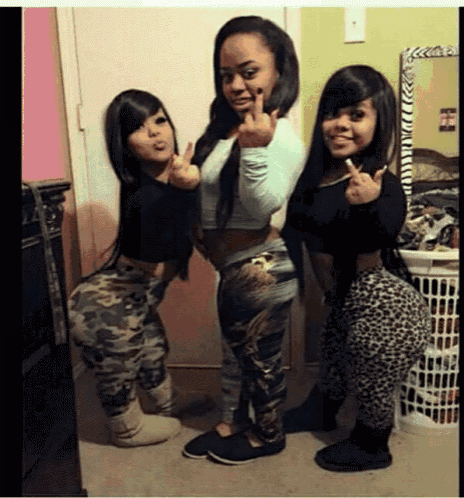 three women are posing for a picture and one is giving a middle finger