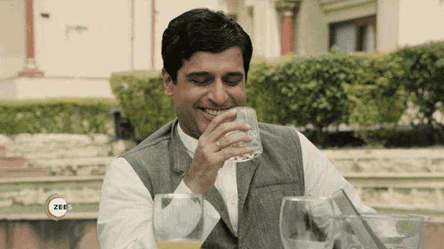 a man drinking from a glass with a zee5 logo on the bottom