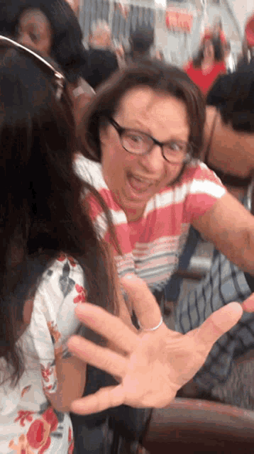 a woman wearing glasses making a funny face with her hand out
