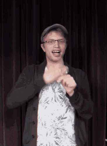 a young man wearing glasses and a hat is making a funny face