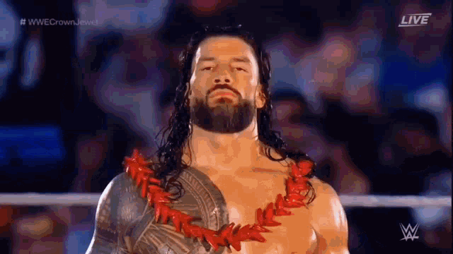 roman reigns is wearing a lei around his neck while standing in a wrestling ring .