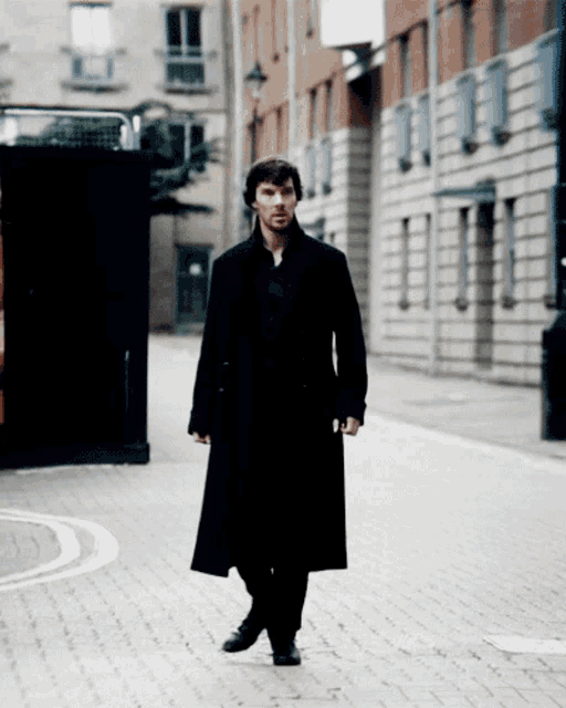 a man in a long black coat is walking down a street