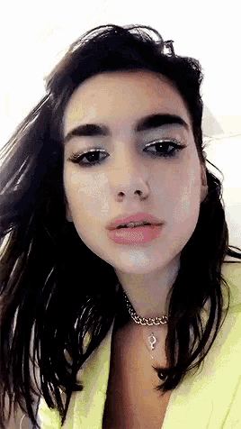 a close up of a woman wearing a yellow jacket and a choker necklace .