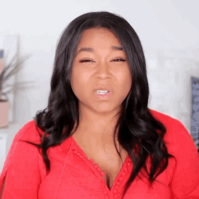 a woman in a red top is making a funny face .