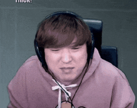 a man wearing headphones and a pink sweatshirt is sitting in a chair .