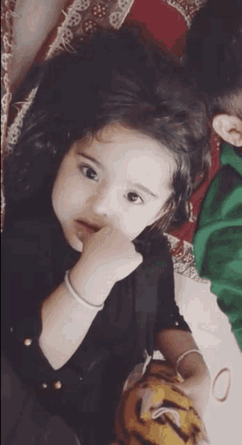 a little girl in a black shirt is laying on the floor