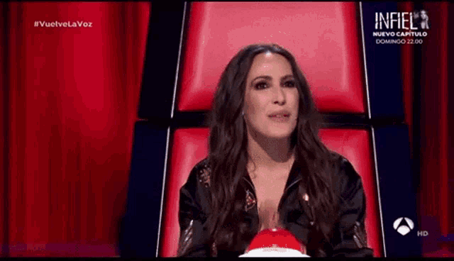a woman is sitting in a chair with the word infiel on the screen