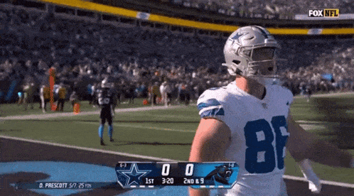 a football player in a cowboys uniform is standing on the field