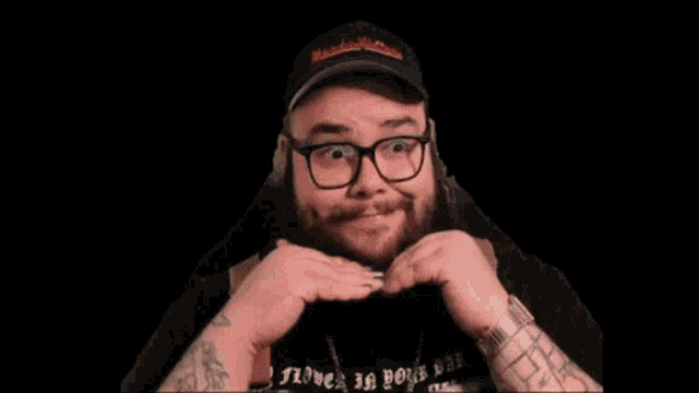 a man with a beard and glasses is making a funny face with his hands .